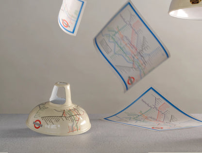 An Original Underground Map shade on a table. In the background, three 1933 maps are falling from the ceiling